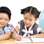 Asian kids are happily studying with blurred globe over white background